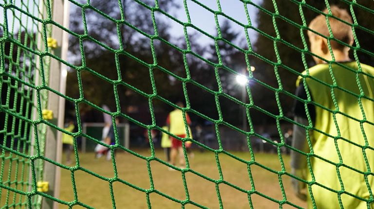 A child is standing in goal at a football match.