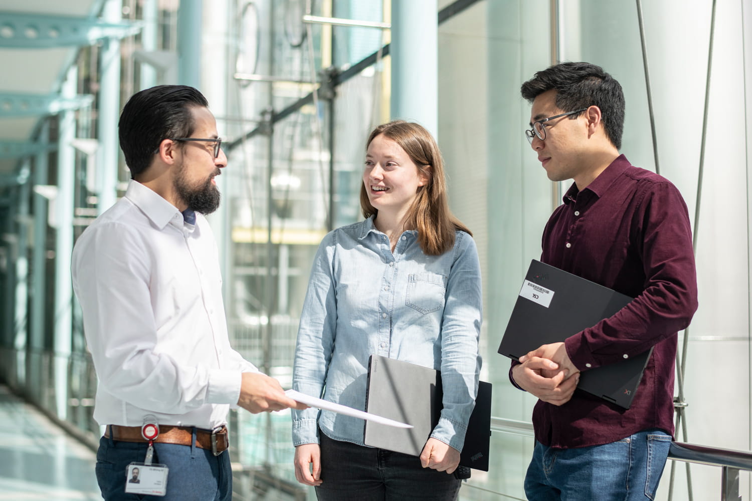 Drei junge Berufstätige, die in einem Gang miteinander reden