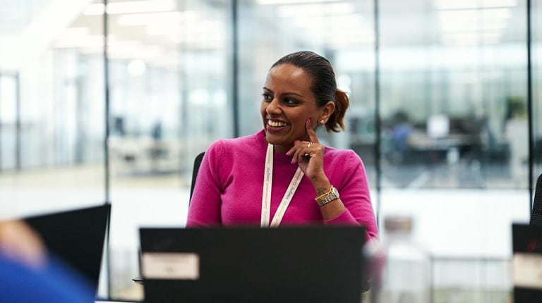 woman in a pink sweater smiles in a meeting