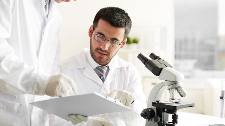 Two male scientist looking at a clipboard