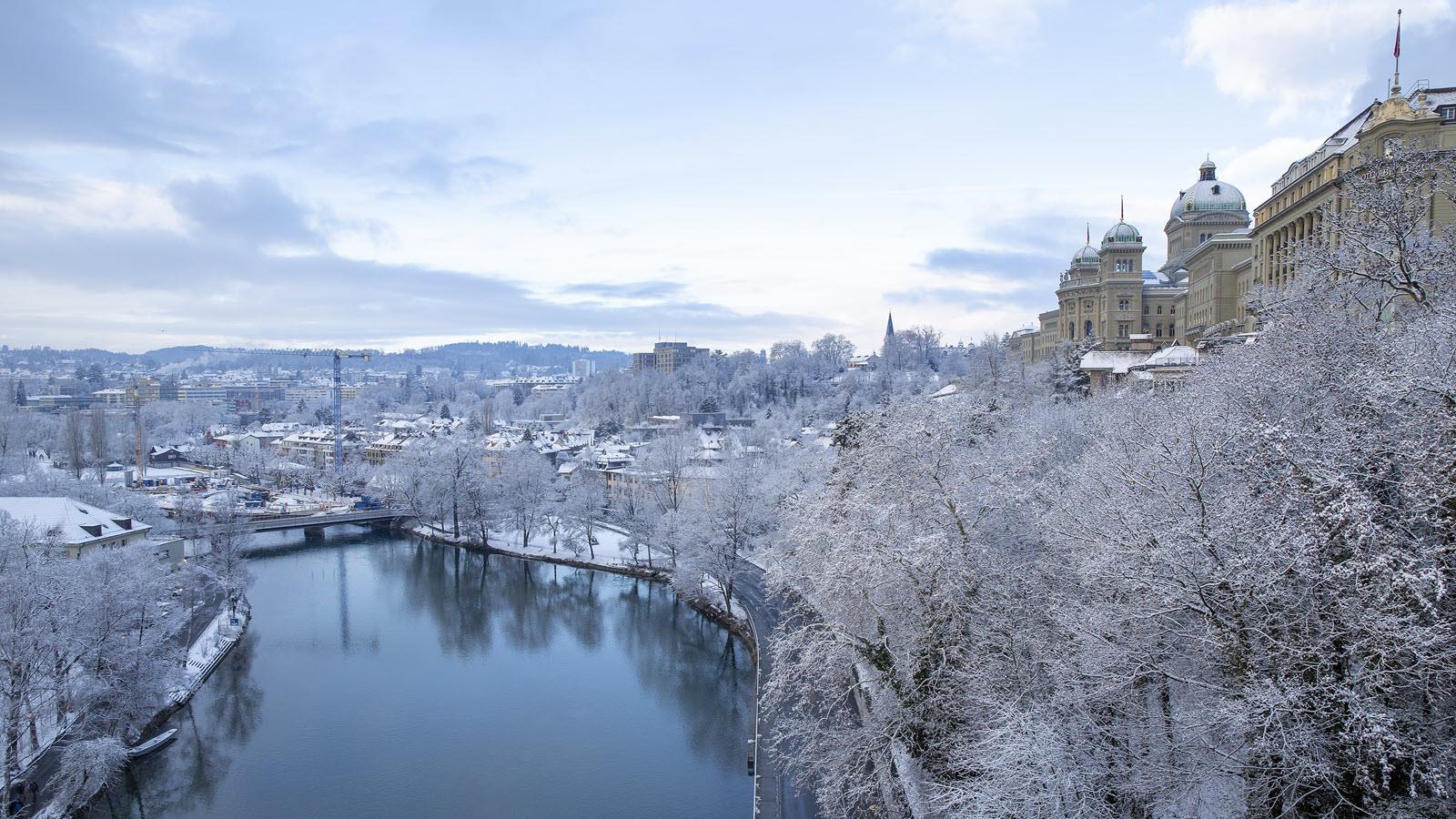 A frosty Bern, Switzerland, along the Aare River with ice-coated trees.
